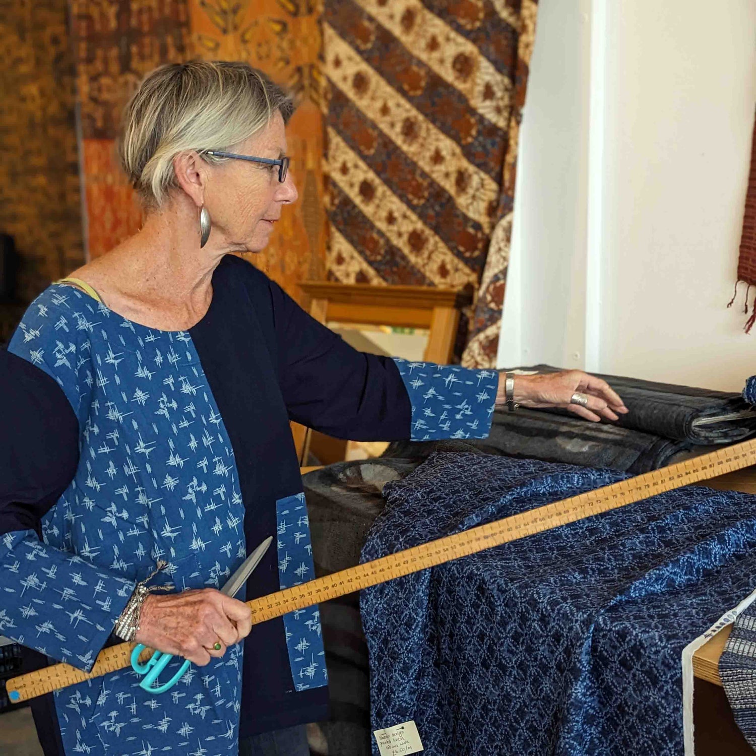 A woman measures fabric by the metre at a UK textiles market.