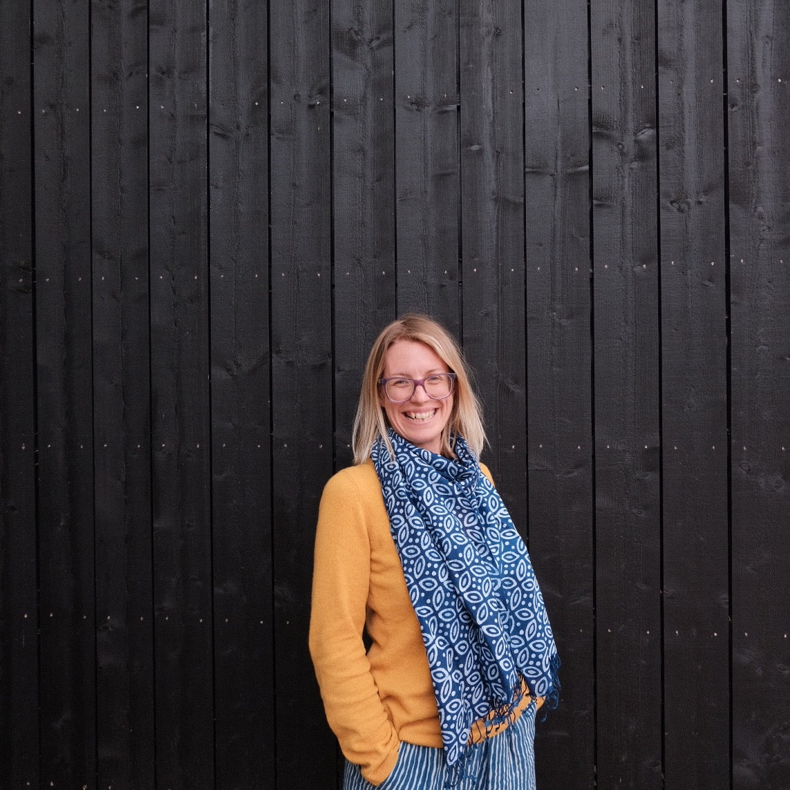 Woman wearing a geometric patterned indigo batik scarf.