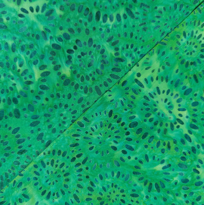 hand printed batik fabric with a teal firework pattern on a bright green cotton background