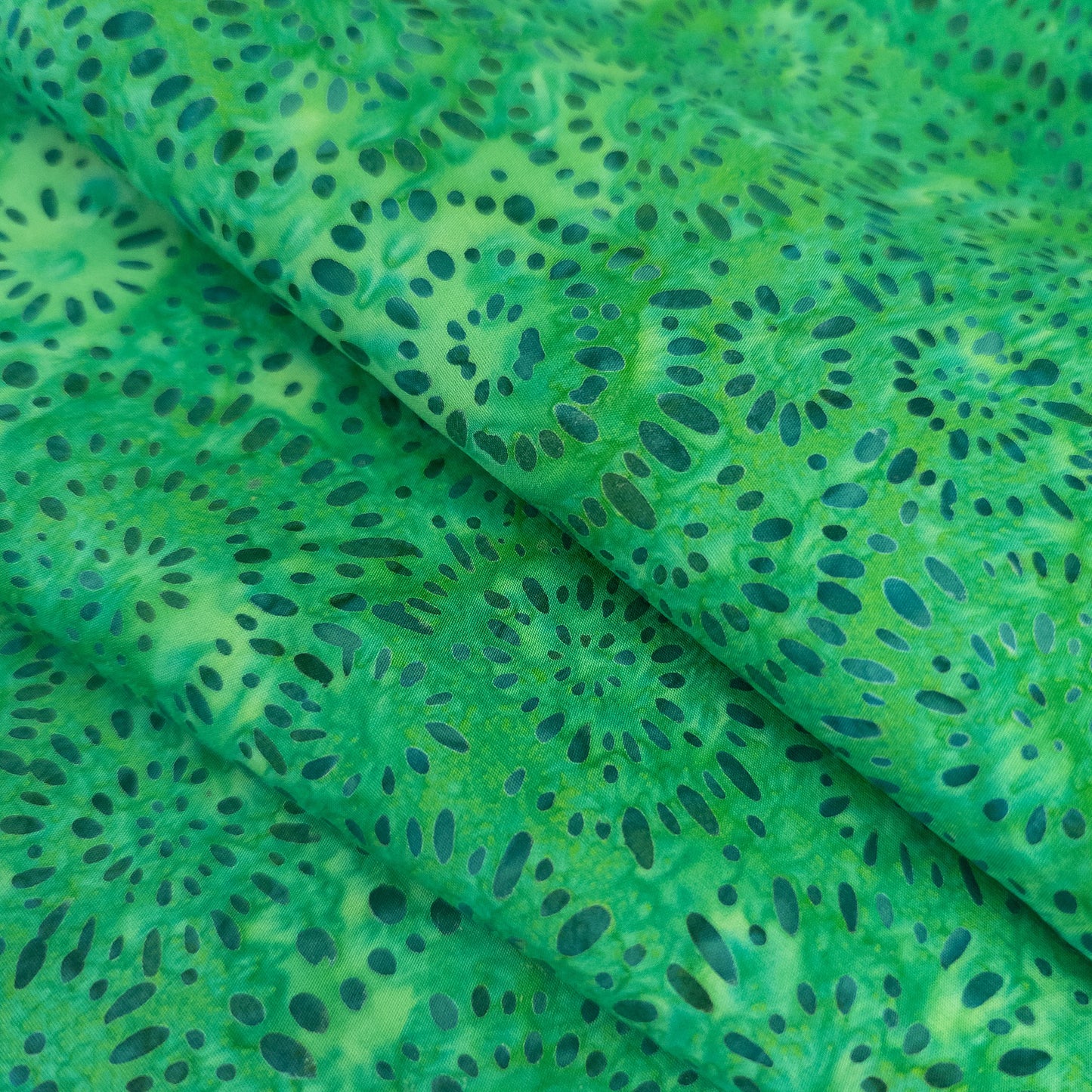 Handprinted green batik with teal firework print design.