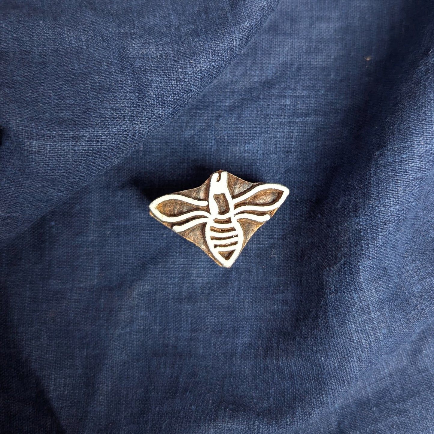 A carved wood block printing stamp in the shape of a honey bee