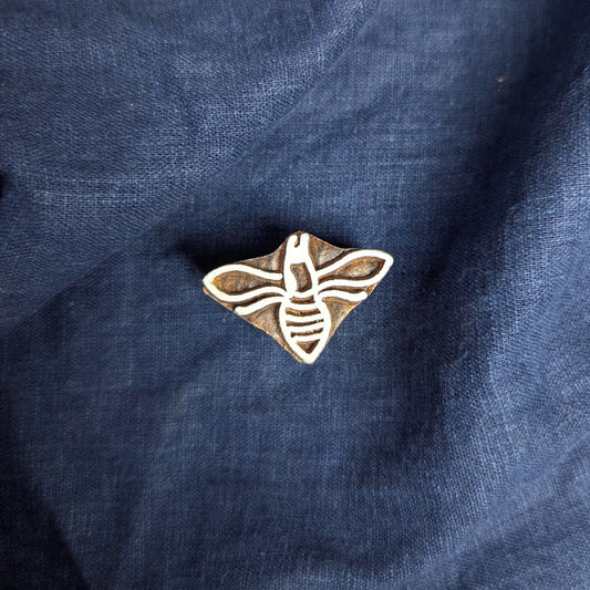 A carved wood block printing stamp in the shape of a honey bee