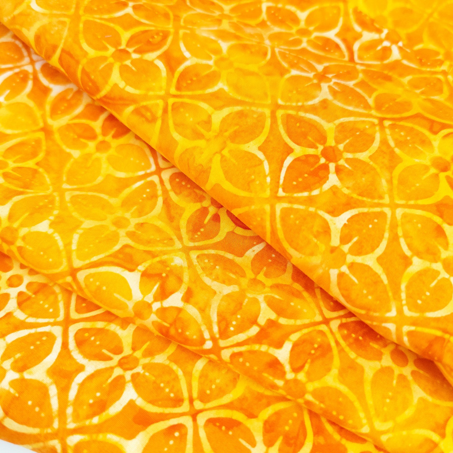Bright orange batik fabric with a geometric tiled flower print.