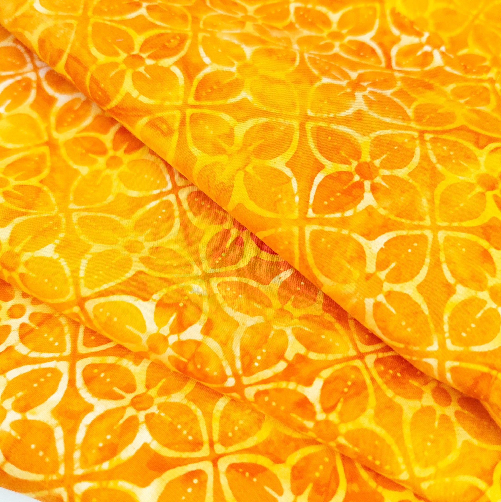 Bright orange batik fabric with a geometric tiled flower print.