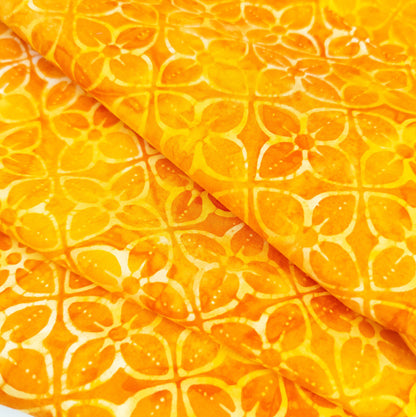 Bright orange batik fabric with a geometric tiled flower print.