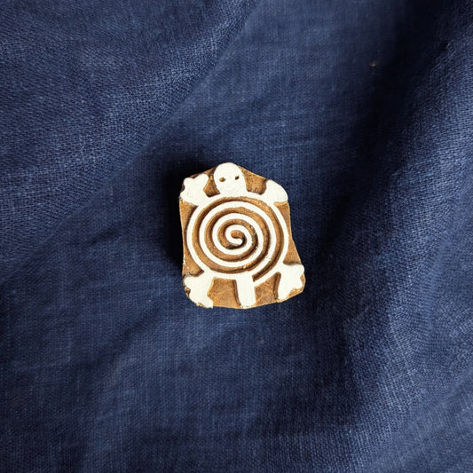 Small carved wooden printing block with turtle design